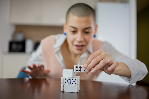 Happy young woman pushing domino pieces