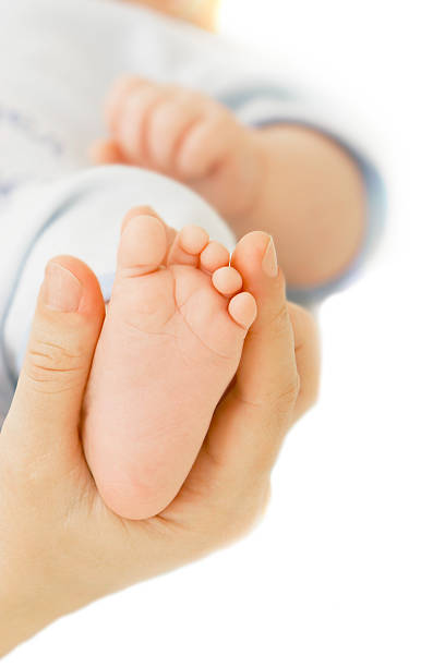 istock baby's foot in parent's hands over white 146952044