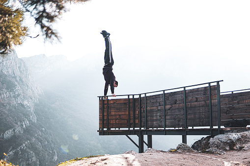 Person doing extreme hand standing, upside down. Doing handstand on egde of a viewpoint on a mountain, street workout, calisthenics