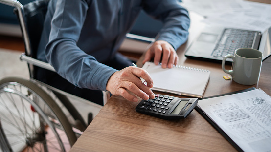 Close-up Adult Man in wheelchair uses calculator