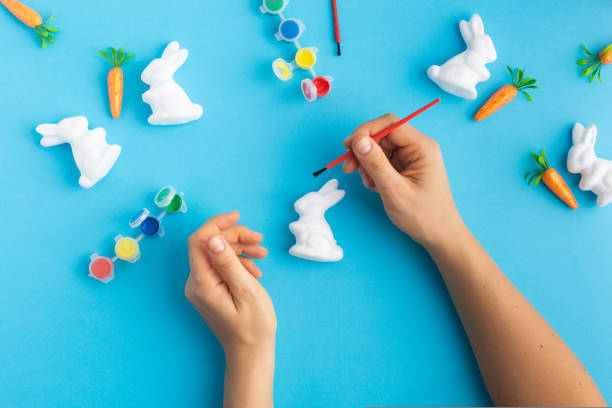easter white rabbits ready to paint carrots concept hands. High quality photo