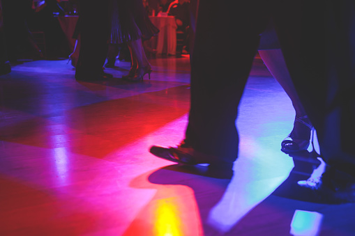 Couples dancing traditional latin argentinian dance milonga in the ballroom on a festival, tango studio, salsa, bachata and kizomba lesson in the red and purple lights, rehearsal in dance class