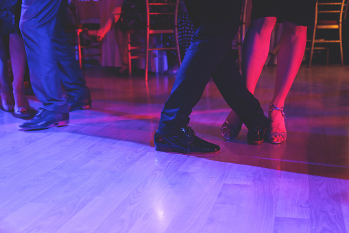 Couples dancing traditional latin argentinian dance milonga in the ballroom on a festival, tango studio, salsa, bachata and kizomba lesson in the red and purple lights, rehearsal in dance class