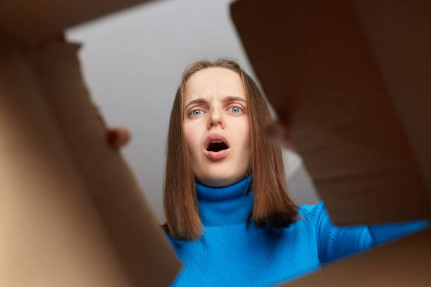 istock Surprised man unpacking, opening carton box and looking inside with big eyes, showing shock. Delivery service, shopping. View from the bottom of cardboard box. 1469529373