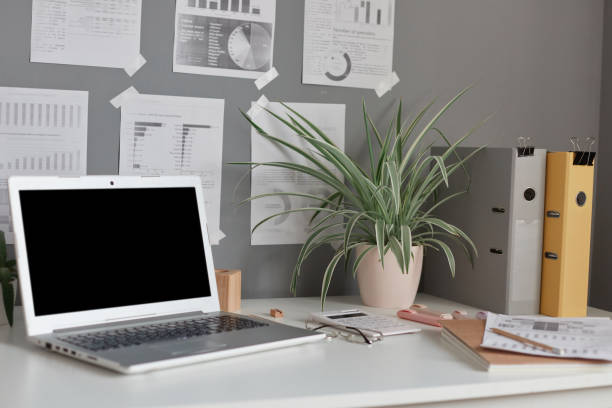 istock Workplace at home or in office with table, laptop with empty display, flower, paper folders, notes on wall. 1469529437