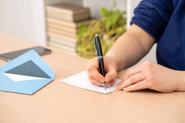 woman writing a greeting card or thank you card Close up of woman hand writing greeting thank you card sitting on a desk at home gift tag note stock pictures, royalty-free photos & images