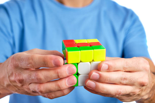 man in blue t-shirt holding rubik's cube with both hands closeup on white background