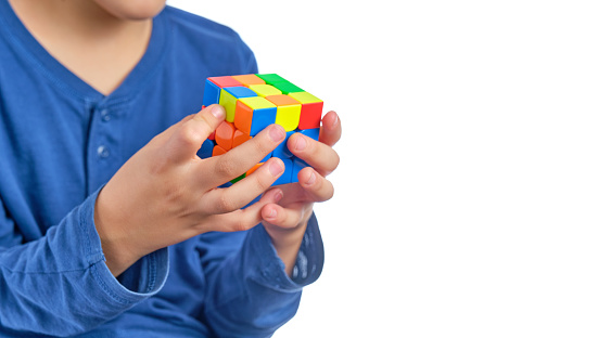 unrecognizable child with rubik's cube in hands on pure white background