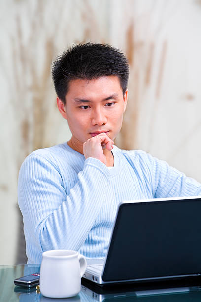 istock Young Chinese man thinking in front of his laptop 146953247