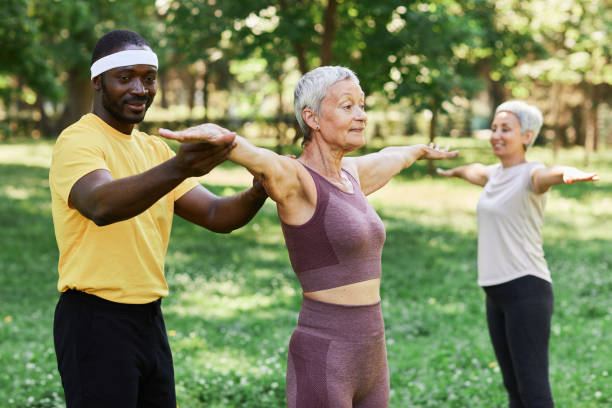 istock Smiling trainer assisting senior woman working out outdoors in park 1469533704