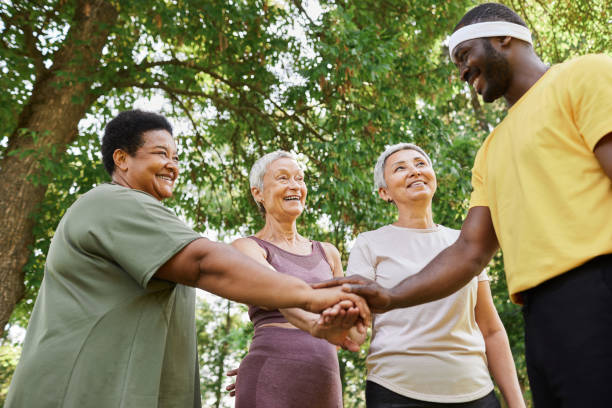 istock Group of active senior women stacking hands with trainer after outdoor workout 1469533780