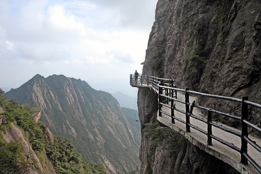 Huangshan, Anhui, China- May 23, 2020: The Yellow Mountains is one of the most famous and beautiful mountainous areas in China. It was listed as a World Heritage Site by UNESCO in 1990. Its spectacular natural scenery includes oddly-shaped pines and rocks, and mystical seas of cloud. It is one of the most visited scenic destinations in China. Here is the Oddly-Shaped Pine of the Yellow Mountains Greeting-guests Pine looks like a host flings arms out to welcome guest.