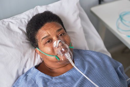Portrait of African American senior woman in hospital room looking at camera, oxygen support
