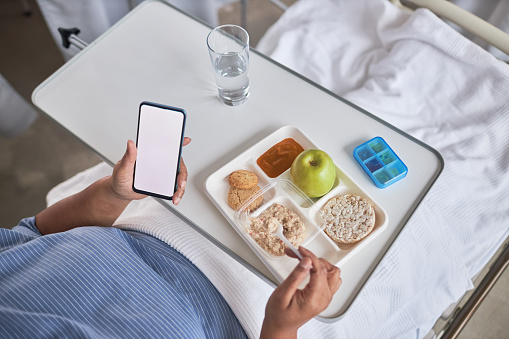 Top view of female patient eating hospital food dinner on tray, copy space