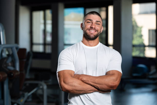 мускулистый мужчина позирует в белой футболке - body building male muscular build posing стоковые фото и изображения