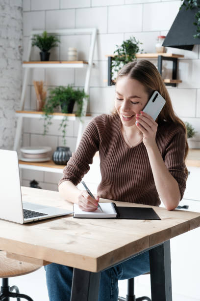 istock Young caucasian businesswoman having a phone call and making notes in a notebook 1469543061