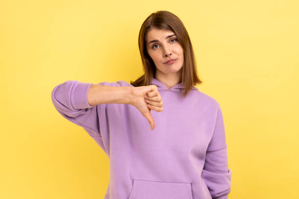 istock Woman standing with thumb down, negative feedback, demonstrating disapproval gesture. 1469545088