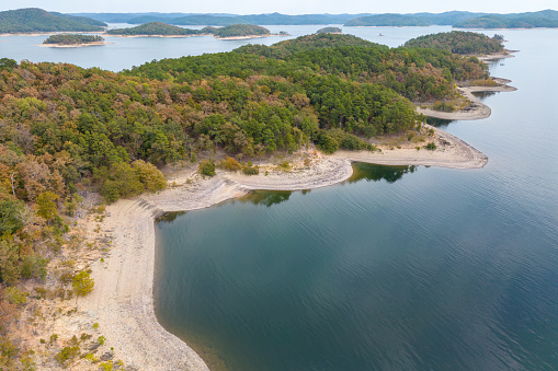 Aerial view of landscape of the surface of the water of Broken Bow lake, Oklahoma, USA. Autumn scenery of coastal line with forest on the bank.