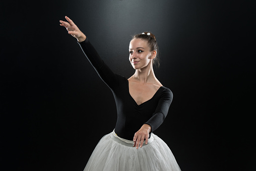 Beautiful Female Ballet Dancer On A Black Background - Ballerina Is Wearing A Tutu And Pointe Shoes