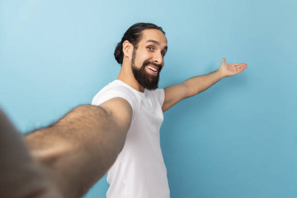 istock Man looking at camera with smile, making welcome gesture, taking selfie POV. 1469546579