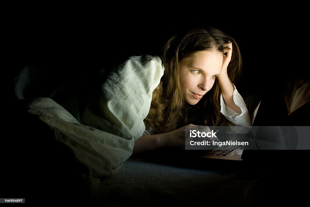 Laptop in bed A young woman working late at night with her laptop in her bed. 20-29 Years Stock Photo