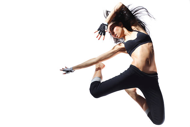 An athletic woman jumping up to strike a fierce pose modern style dancer jumping behind studio background jazz dancing stock pictures, royalty-free photos & images