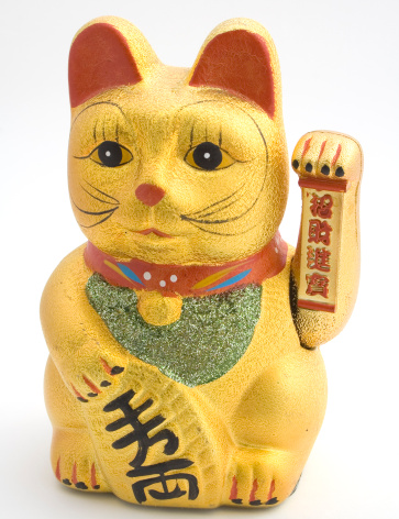 Cute Maneki neko cat waving with paw close up