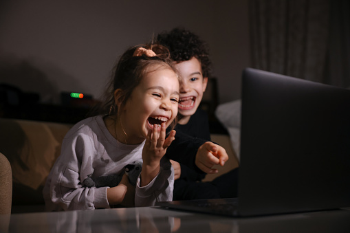 Girl and boy watching a movie on the laptop on sofa  at home