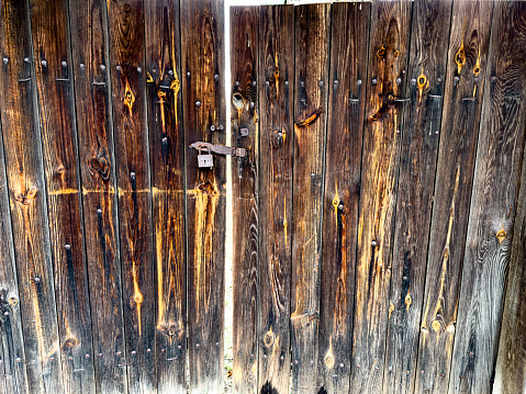 The old wooden door is closed with an old lock. High quality photo