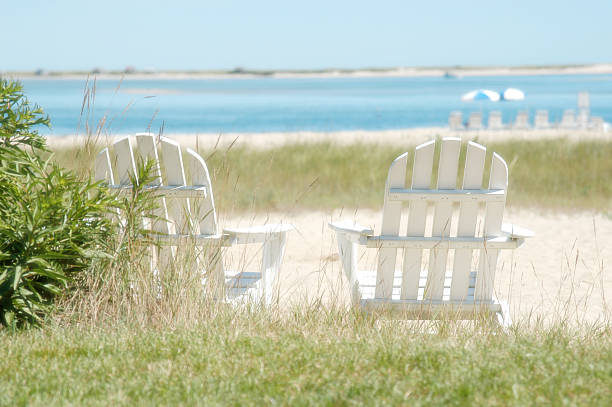 Two white Adirondack chairs near the shore