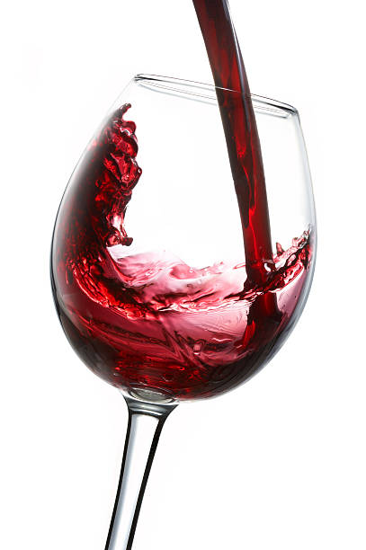Red wine being poured into glas, isolated on white