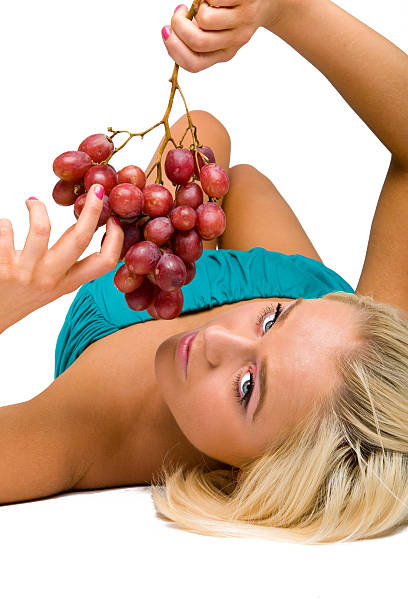 blonde girl in blue with grapes stock photo