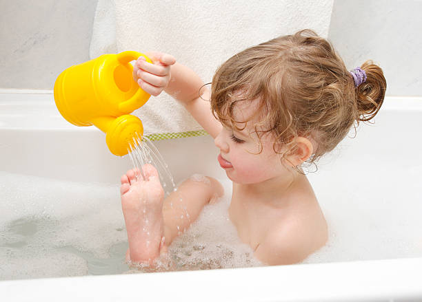 Playing in a bath Little girl is taking a bath, playing with a toy watering-pot. girls bath stock pictures, royalty-free photos & images