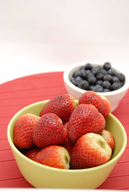 istock Blueberries and strawberries in green bowl over red 146957005