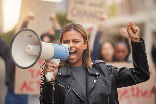istock Justice, megaphone and shouting with woman in protest for equality, freedom and support for change. Global fight, social and future with girl in crowd for human rights, community and revolution 1469579990