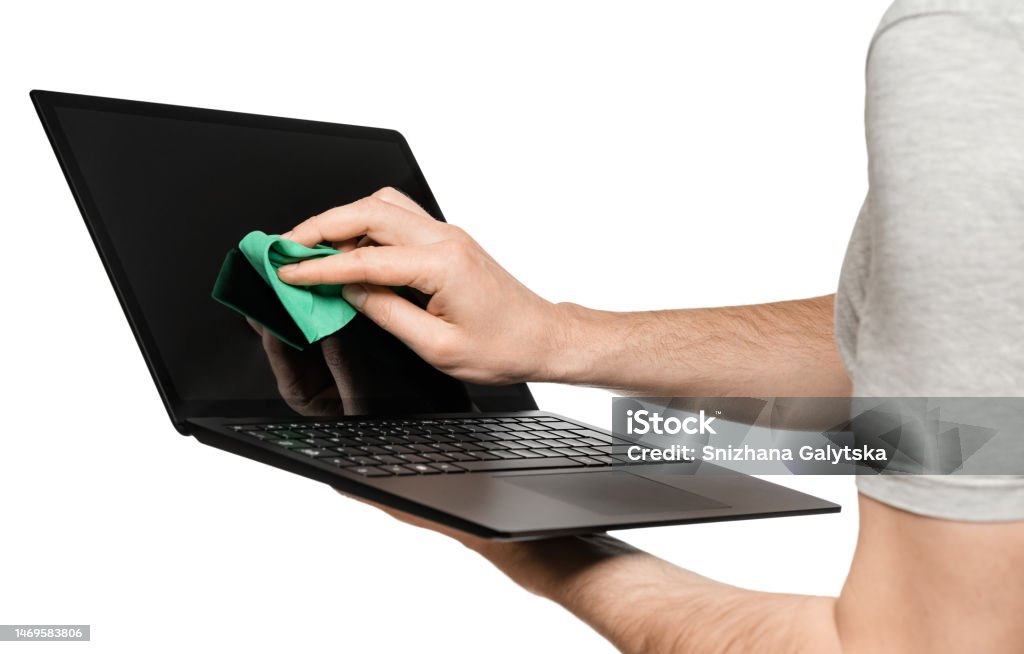 A man holds a laptop in one hand, the other wipes the touch screen. Isolate on a white background. Laptop in male hand with green screen. Slim ultrabook in matte black with a touch screen. Slim aluminum laptop. Adult Stock Photo