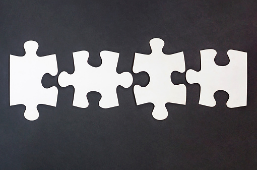 Four disconnected jigsaw puzzle pieces in row on black background