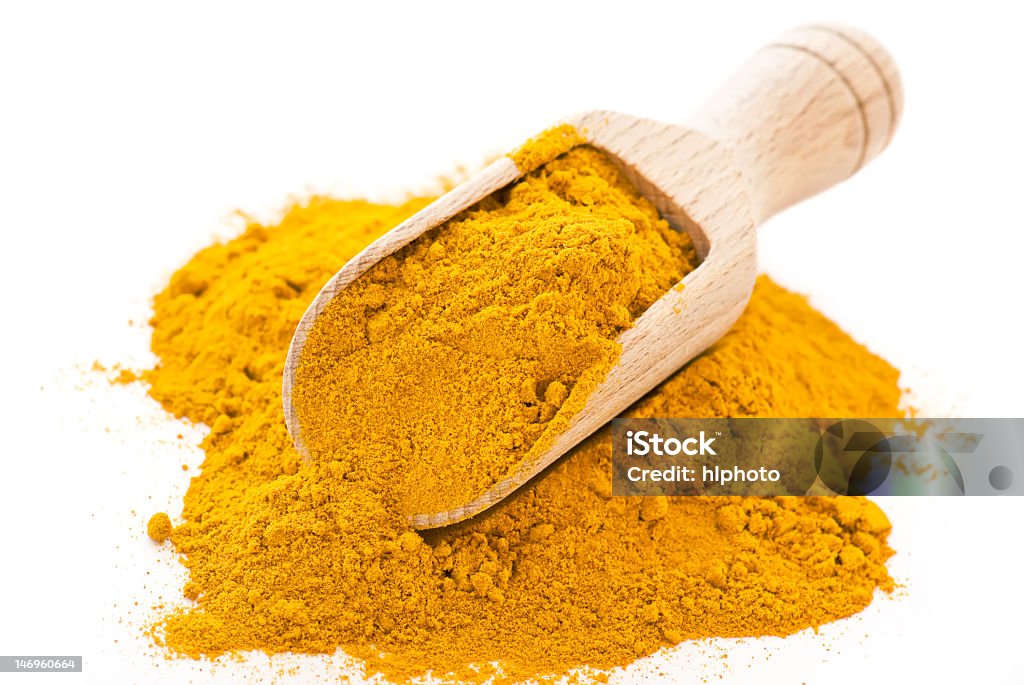 A pile of curry powder with a scoop in it Dried curry powder with shovel as closeup on white background Allspice Stock Photo