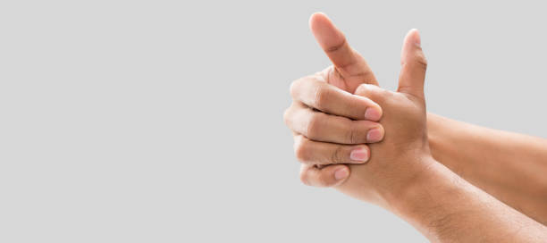 Cracking their knuckles A man cracking their knuckles, On a gray background. knuckle joint stock pictures, royalty-free photos & images
