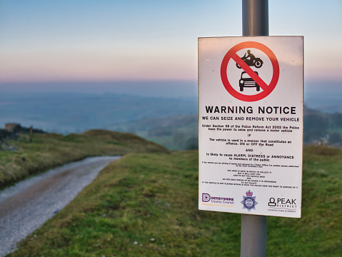 A warning sign on a walking trail in the Derbyshire countryside advises that offending vehicles causing alarm, distress or annoyance can be seized and removed.