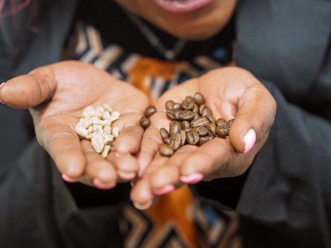 hand of african american woman holding coffee beans macro close up