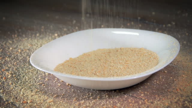 Sprinkle breadcrumbs in tray for cook, slow motion