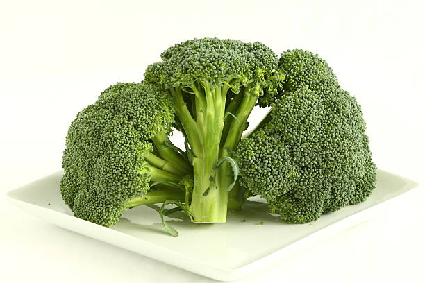 Broccoli Crowns Three broccoli crowns on a white plate. broccoli crowns stock pictures, royalty-free photos & images