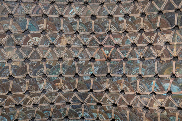 Close up asian coins with patina coloring interwoven together in rows with natural jute