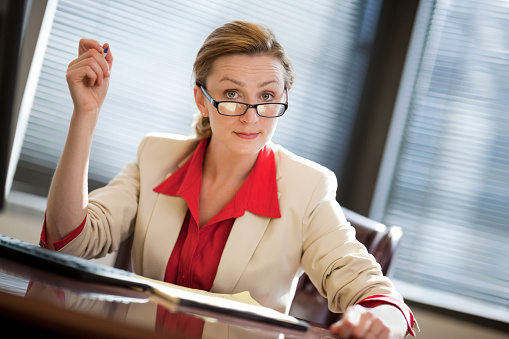Young woman sitting at desk in office appearing to be perturbed judging by the look on face.