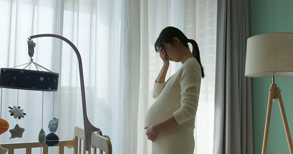 pregnant woman feel depression standing in front of window