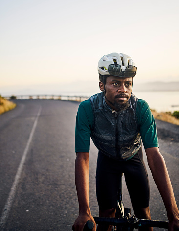 Fitness, looking and black man cycling on the street for exercise, training and race in Spain. Thinking, sports and African athlete on a bike for a workout, sport and cardio on the road with vision