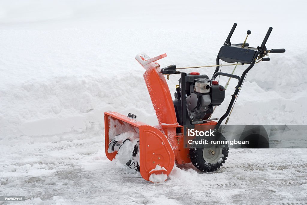 Red snowblower on a road beside white snow Brand new snowblower after clearing 12" snow off the driveway. Snowblower Stock Photo