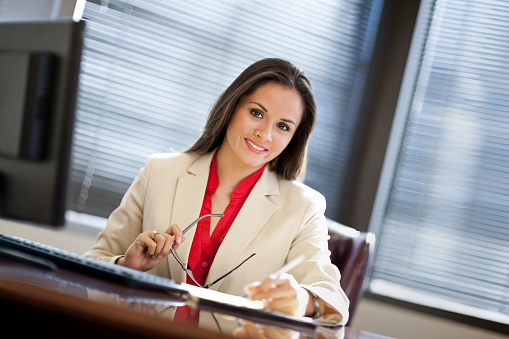 Young business woman sitting at computer and smiling at the camera.