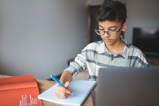 Boy using laptop studying online at home